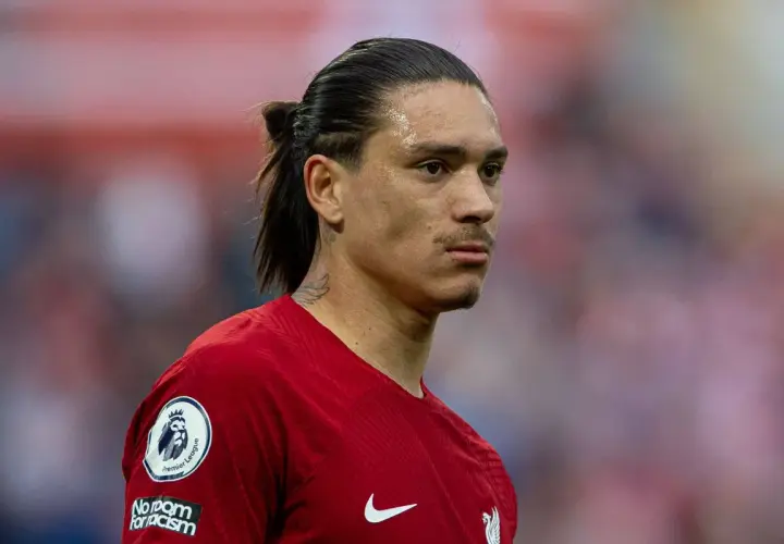 Darwin Nunez w czerwonej koszulce Liverpoolu, z charakterystycznym kucykiem i tatuażem na szyi, gotowy do gry.