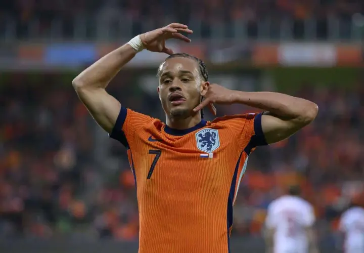 Piłkarz Xavi Simons w pomarańczowej koszulce reprezentacji Holandii z numerem 7, z rękami przy głowie.