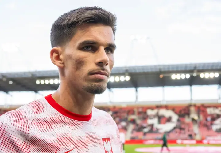 Filip Marchwiński w biało-czerwonej koszulce z godłem Polski, na tle stadionu.