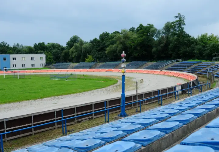 Puste trybuny stadionu Wandy Kraków z widokiem na tor żużlowy i boisko.