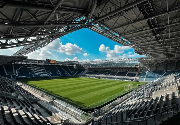 Puste trybuny stadio Atleti Azzurri d'Italia czekają na kibiców. Zielona murawa lśni w słońcu, gotowa na emocje.