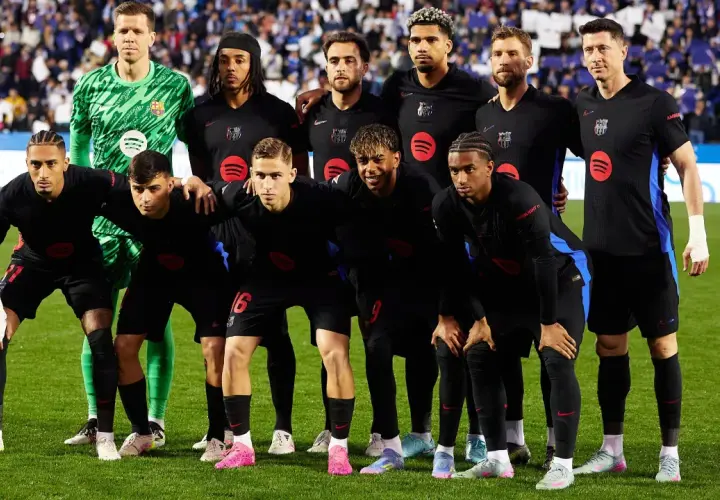 Drużyna FC Barcelona, znana z hiszpańskich zawodników, pozuje do zdjęcia w czarnych strojach.