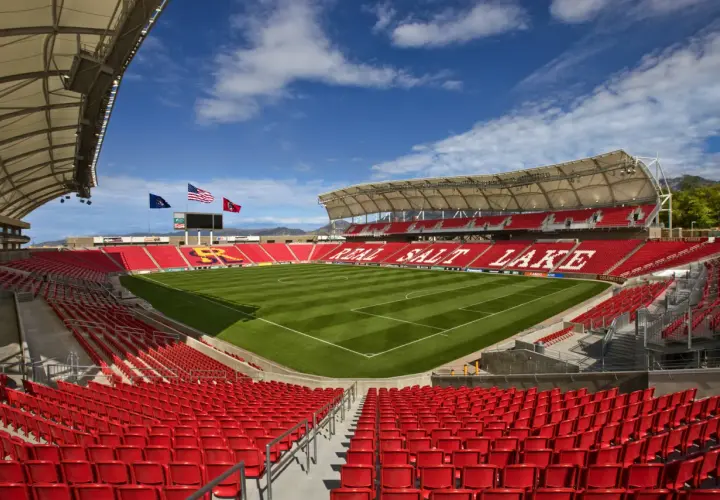 Puste trybuny stadionu Real Salt Lake, z zieloną murawą i niebieskim niebem.