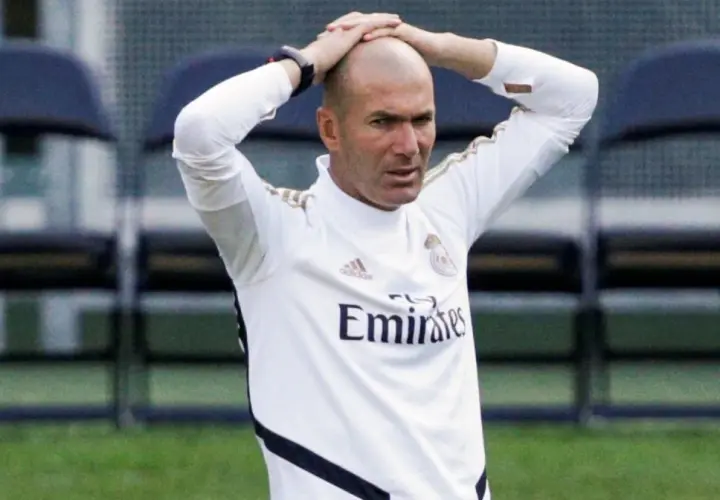 Zinedine Zidane, trener Real Madryt 2017, z rękami na głowie, w białej koszulce treningowej.