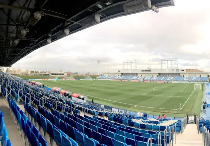 Puste trybuny stadionu Alfredo Di Stéfano, z zieloną murawą i niebieskimi siedzeniami, czekają na kibiców.