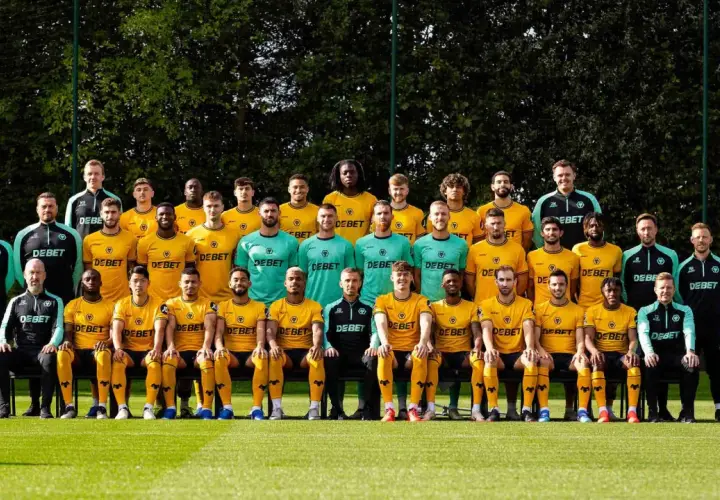 Wolverhampton Wanderers F.C. – zawodnicy w żółtych i zielonych strojach pozują do zdjęcia drużynowego na boisku.