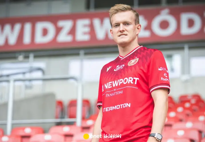 Piłkarz Karol Świderski w czerwonej koszulce Widzewa Łódź. Jego zarobki budzą zainteresowanie kibiców.
