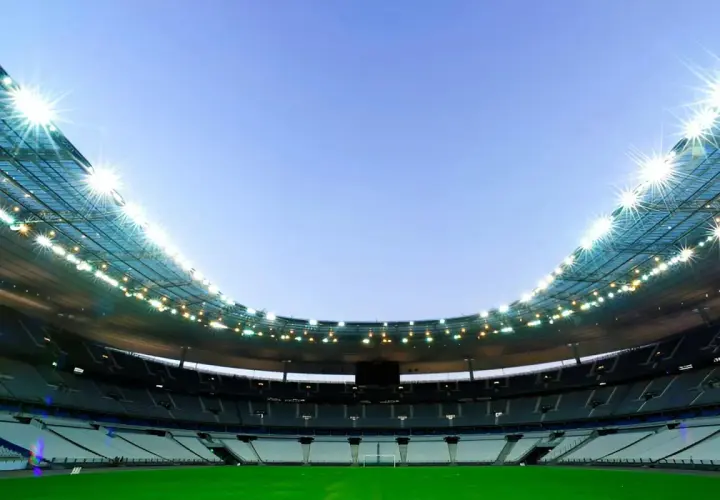 Puste trybuny Stade de France czekają na kibiców. Jasne światła oświetlają zieloną murawę.