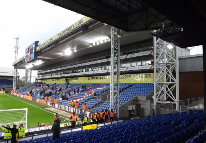 Puste trybuny stadionu Crystal Palace, z widokiem na murawę i tablicę wyników.
