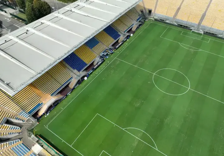 Puste trybuny stadionu Ennio Tardini, z zieloną murawą i białymi liniami boiska.