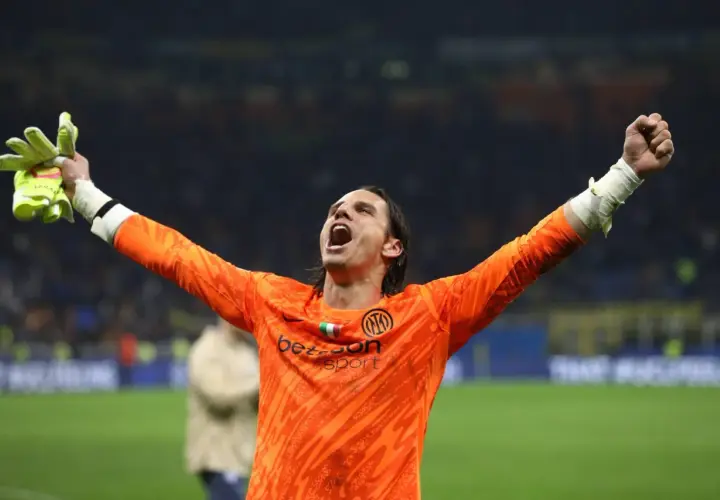 Bramkarz Yann Sommer w pomarańczowej koszulce z podniesionymi rękami świętuje zwycięstwo.