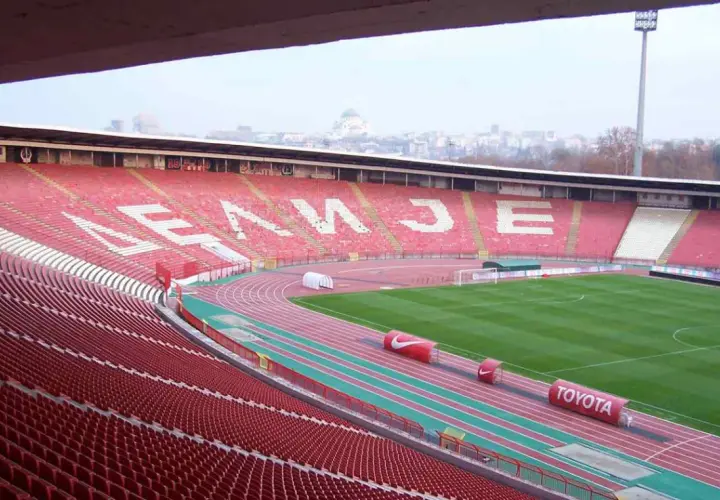 Puste trybuny stadionu Crvena Zvezda czekają na kibiców. Na tle miasta widać charakterystyczną kopułę.
