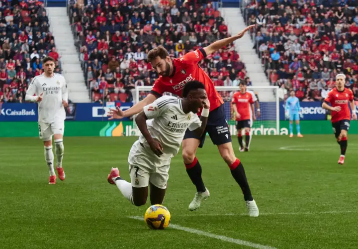 Piłkarze Real Madryt i Osasuna walczą o piłkę na murawie. W tle trybuny pełne kibiców.