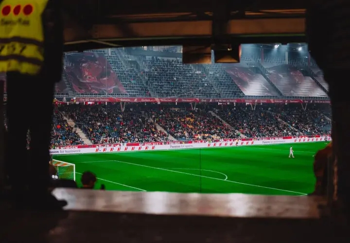 Piłkarz na boisku podczas meczu Wolfsberger – RB Salzburg. Trybuny pełne kibiców, wielkie banery na stadionie.