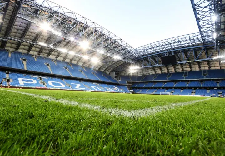 Zielona murawa i niebieskie trybuny stadionu Lecha Poznań, gotowe na kolejny mecz.