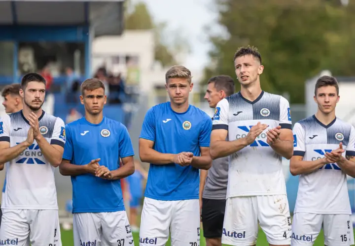 Pięciu młodych piłkarzy Hutnika Kraków w strojach klubowych stoi w rzędzie, klaszcząc.