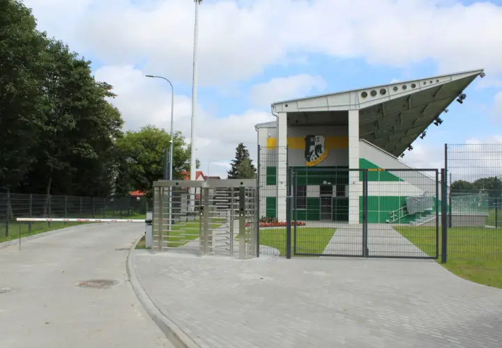 Nowoczesny stadion w Białej Podlaskiej z trybunami, bramami i obrotowymi kołowrotkami.