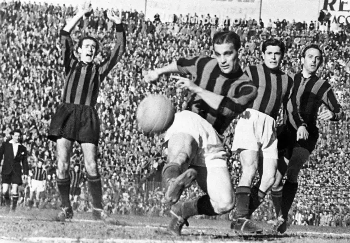 A.C. Milan – zawodnicy w akcji. Piłkarze w pasiatych koszulkach walczą o piłkę na tle trybun pełnych kibiców.