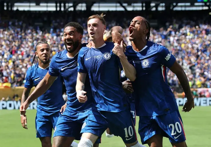 Radość zawodników Chelsea F.C. po zdobytej bramce. Piłkarze w niebieskich strojach świętują razem na boisku, otoczeni przez kibiców.