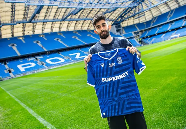 Ali Gholizadeh prezentuje nową koszulkę Lecha Poznań na tle stadionu.