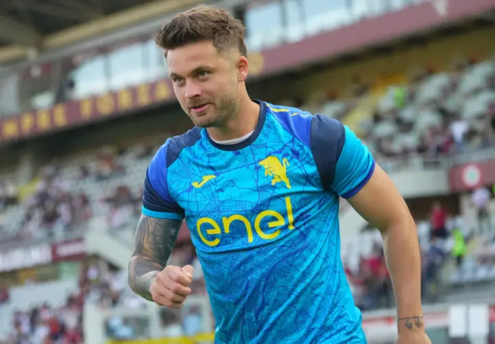Piłkarz w błękitnej koszulce z żółtym logo "enel" i bykiem, widać trybuny stadionu. To moment, kiedy gra Linetty.