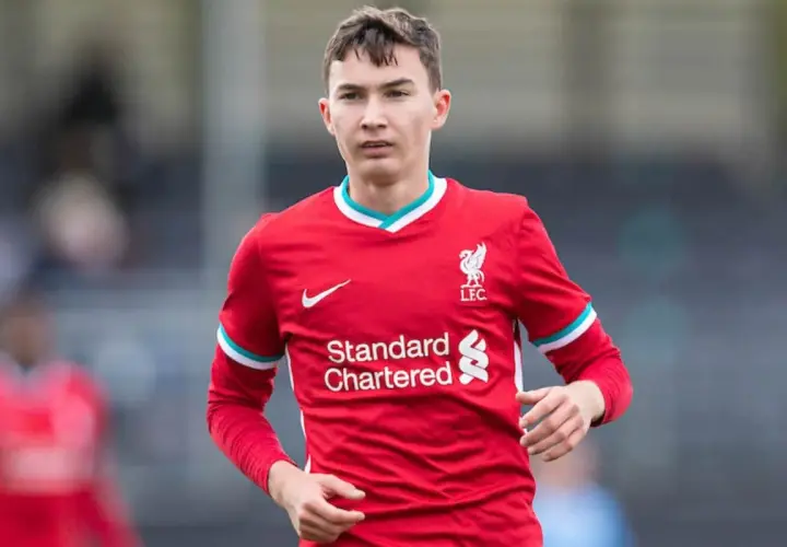 Młody piłkarz Mateusz Musiałowski w czerwonej koszulce Liverpoolu, z dumą nosi herb klubu.