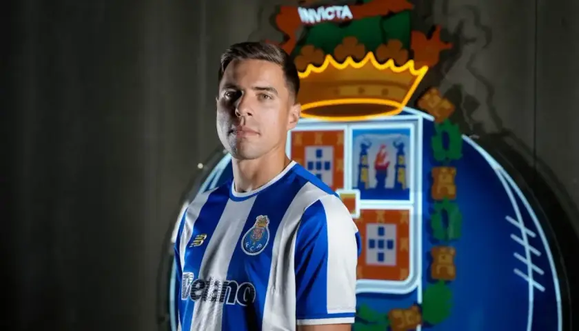 Piłkarz w koszulce FC Porto, gdzie gra Bednarek. Za nim neonowy herb klubu.