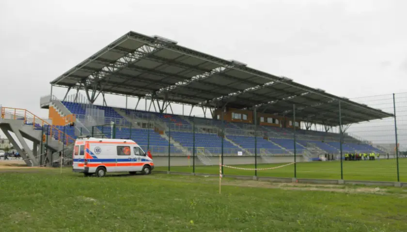 Pogoń Siedlce stadion z ambulansem na murawie. Puste trybuny czekają na kibiców.