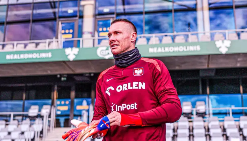 Bramkarz w bordowej koszulce z orłem, gotowy do gry. Gdzie gra Skorupski? Na stadionie, wśród pustych trybun.