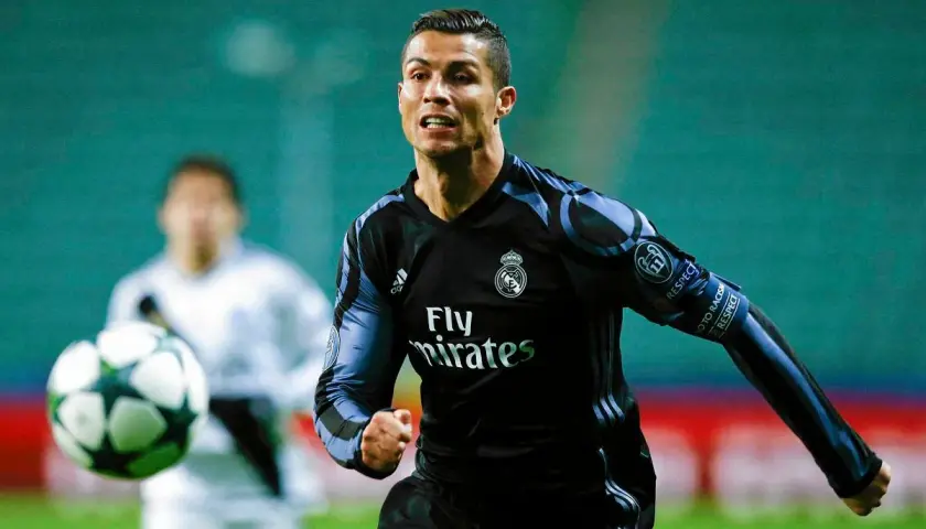 Cristiano Ronaldo w czarnej koszulce Realu Madryt biegnie z piłką.