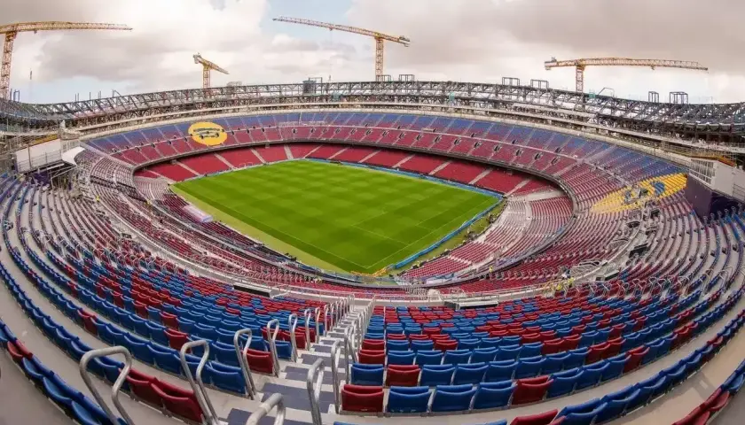 Widok na Camp Nou, największy stadion w Hiszpanii, w trakcie modernizacji. Żurawie budowlane górują nad trybunami w barwach czerwono-niebieskich.
