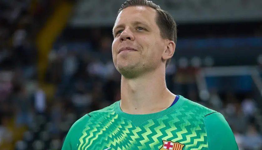 Wojciech Szczęsny w zielonej bramkarskiej koszulce, z uśmiechem na twarzy, gotowy do gry.