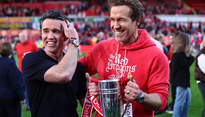 Ryan Reynolds i Rob McElhenney świętują sukces Wrexham A.F.C. z pucharem. Ich radość odzwierciedla pozytywne rankingi klubu.