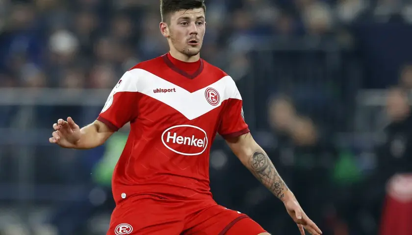 Jeden z zawodników Hertha BSC w czerwonej koszulce z białymi elementami i logo "Henkel" na piersi, z tatuażem kompasu na ramieniu.