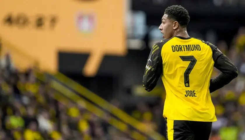 Piłkarz Jobe Bellingham w żółtej koszulce z numerem 7 i napisem "DORTMUND" na plecach, na tle trybun.