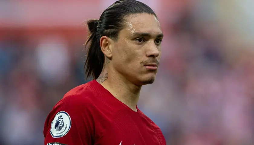 Darwin Nunez w czerwonej koszulce Liverpoolu, z charakterystycznym kucykiem i tatuażem na szyi, gotowy do gry.