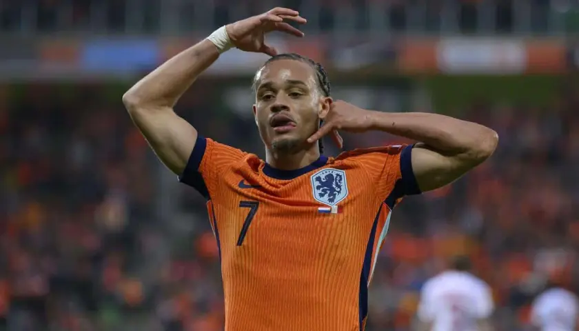 Piłkarz Xavi Simons w pomarańczowej koszulce reprezentacji Holandii z numerem 7, z rękami przy głowie.