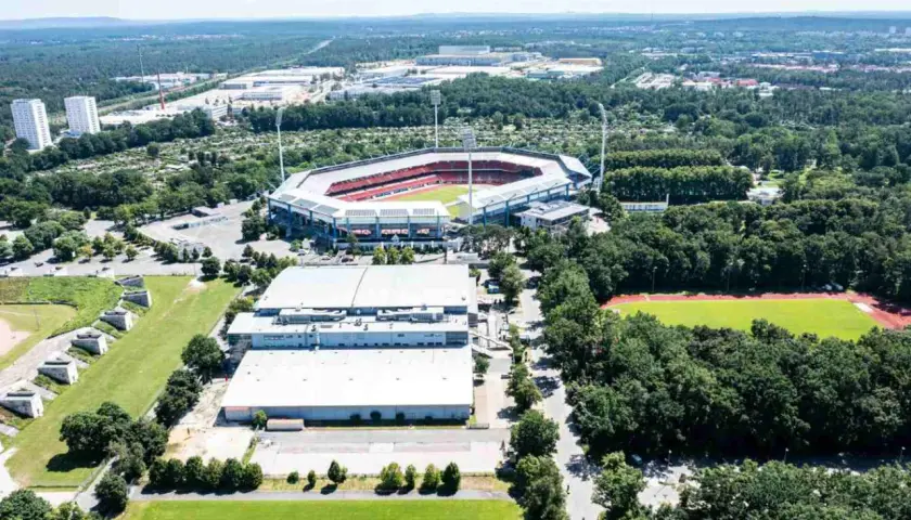 Widok z lotu ptaka na Max-Morlock-Stadion otoczony zielenią, z pobliskimi budynkami i boiskiem sportowym.