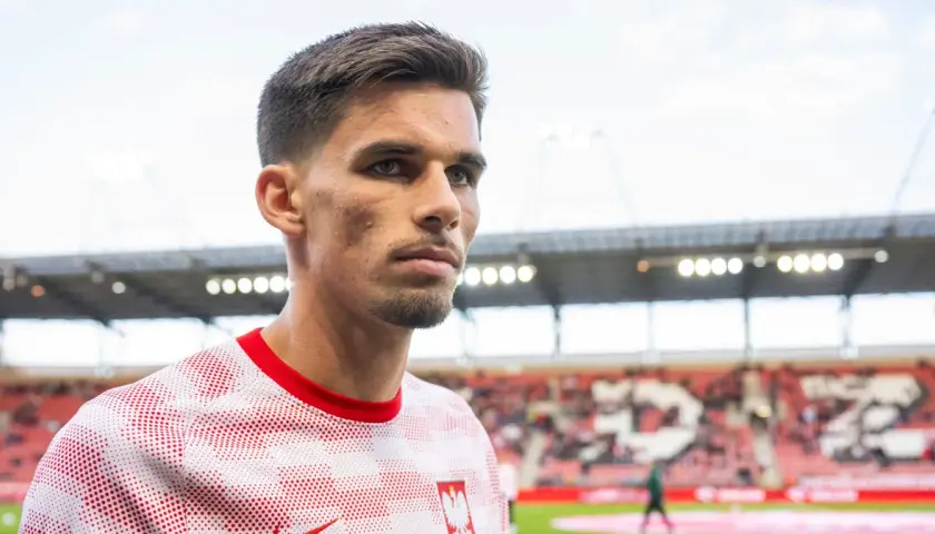 Filip Marchwiński w biało-czerwonej koszulce z godłem Polski, na tle stadionu.
