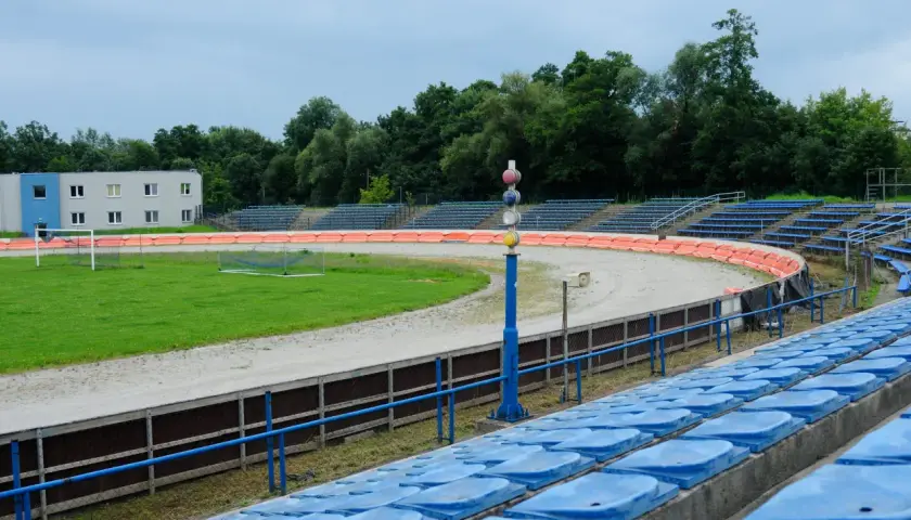 Puste trybuny stadionu Wandy Kraków z widokiem na tor żużlowy i boisko.