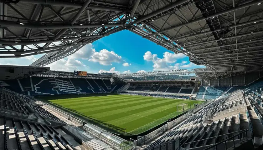 Puste trybuny stadio Atleti Azzurri d'Italia czekają na kibiców. Zielona murawa lśni w słońcu, gotowa na emocje.
