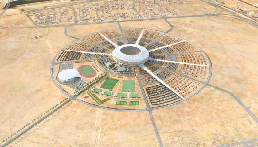 Okrągły kompleks sportowy z centralnym stadionem, otoczony parkingami i boiskami. To wizualizacja King Abdullah Sports City.