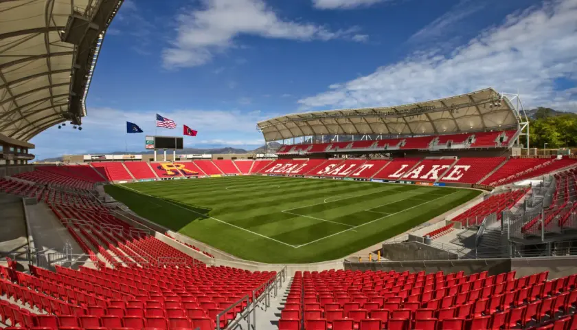 Puste trybuny stadionu Real Salt Lake, z zieloną murawą i niebieskim niebem.