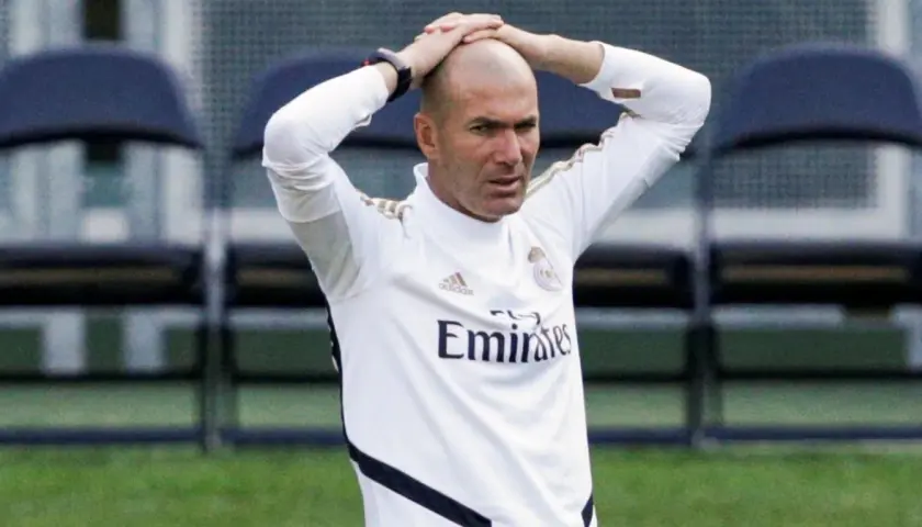 Zinedine Zidane, trener Real Madryt 2017, z rękami na głowie, w białej koszulce treningowej.