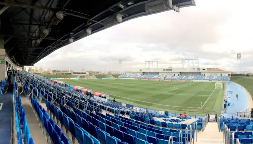 Puste trybuny stadionu Alfredo Di Stéfano, z zieloną murawą i niebieskimi siedzeniami, czekają na kibiców.