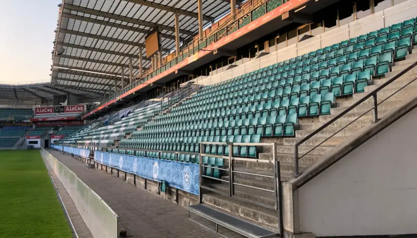 Puste trybuny stadionu A. Le Coq Arena czekają na kibiców. Zielone krzesełka tworzą morze nadziei na emocjonujące mecze.
