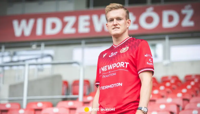 Piłkarz Karol Świderski w czerwonej koszulce Widzewa Łódź. Jego zarobki budzą zainteresowanie kibiców.