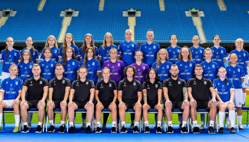 Drużyna piłkarska Lech Poznań UAM w komplecie, gotowa do gry na stadionie.