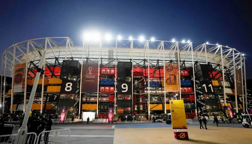 Nocny widok na **stadion z kontenerów Katar** z numerowanymi sekcjami i banerami Mistrzostw Świata FIFA 2022.