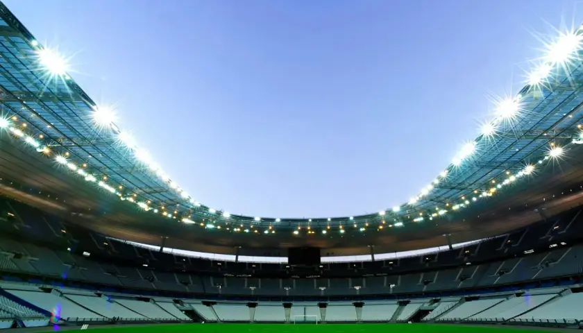 Puste trybuny Stade de France czekają na kibiców. Jasne światła oświetlają zieloną murawę.